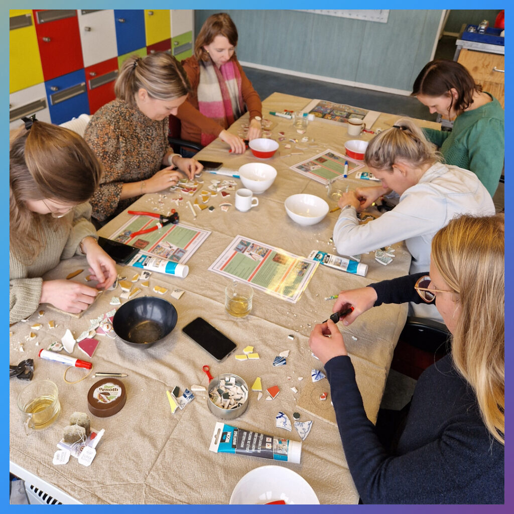 Groep vrouwen maakt mozaïek van serviesstukken.