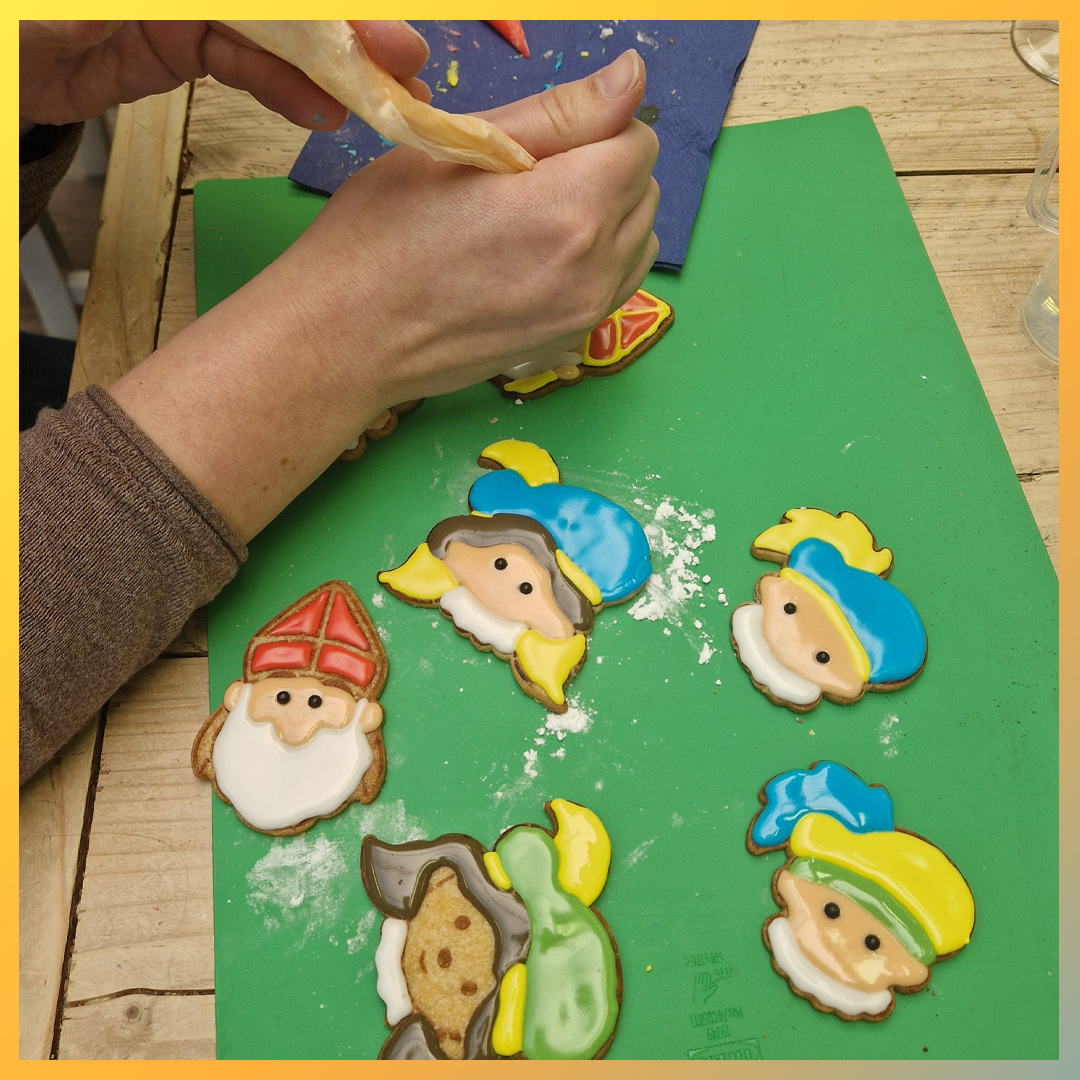 Man versiert Sinterklaas- en Pietenkoekjes met Royal Icing.