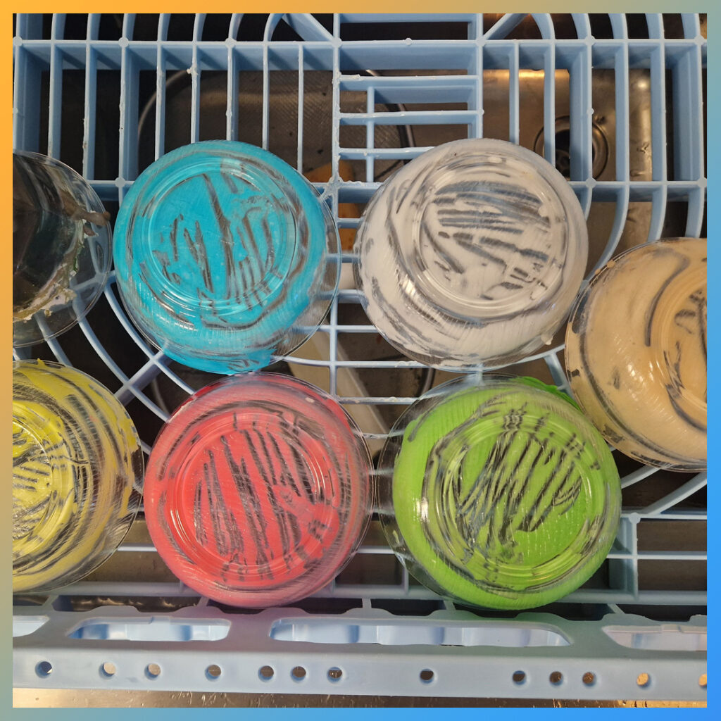 Zeven glazen bakjes met gekleurde Royal Icing in keuken.