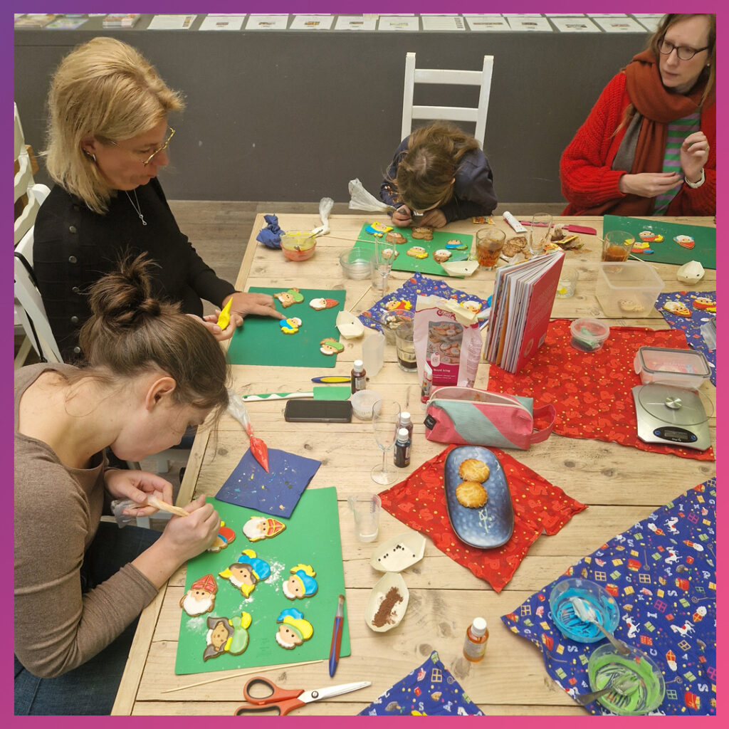 Volwassenen en kind decoreren Sinterklaaskoekjes met Royal Icing.