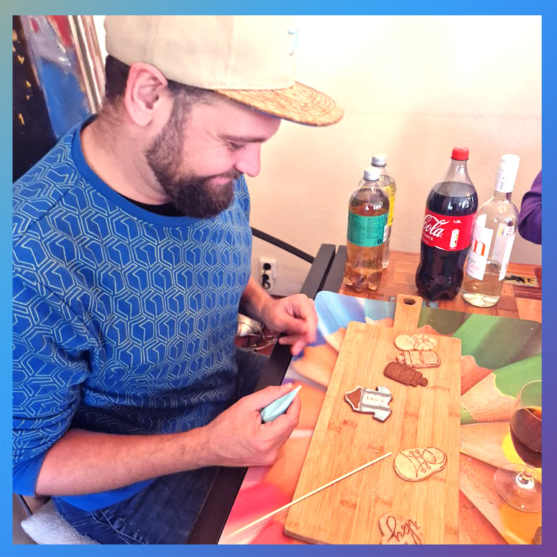 Man versiert babyshower koekjes met royal icing