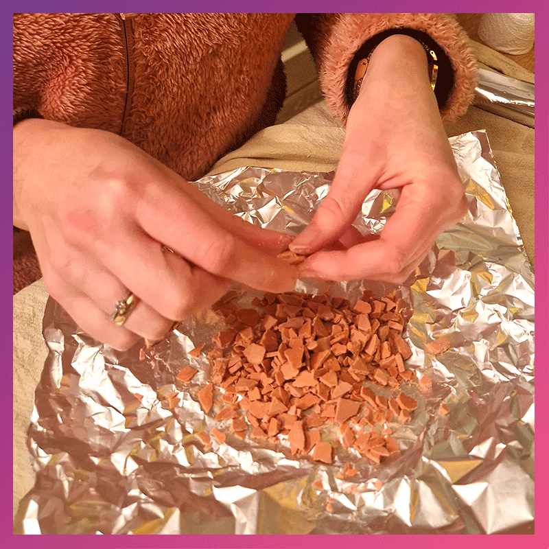 Handen breken opgedroogd composietmateriaal in kleine terrazzo-stukjes voor gebruik in een gietworkshop