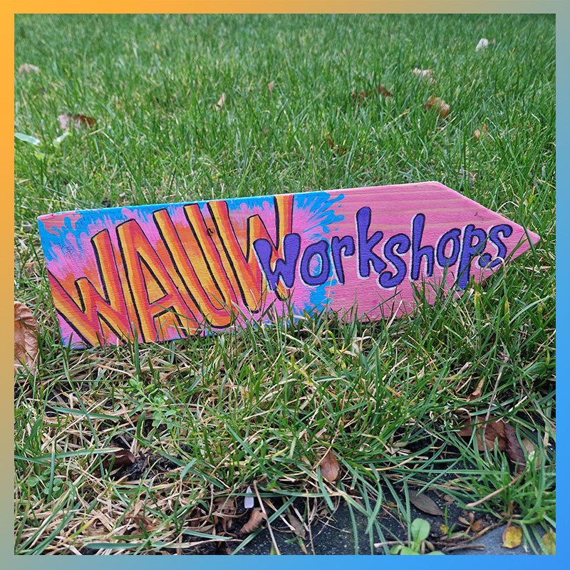 Houten beschilderd wegwijzerbordje met de tekst WAUW Workshops