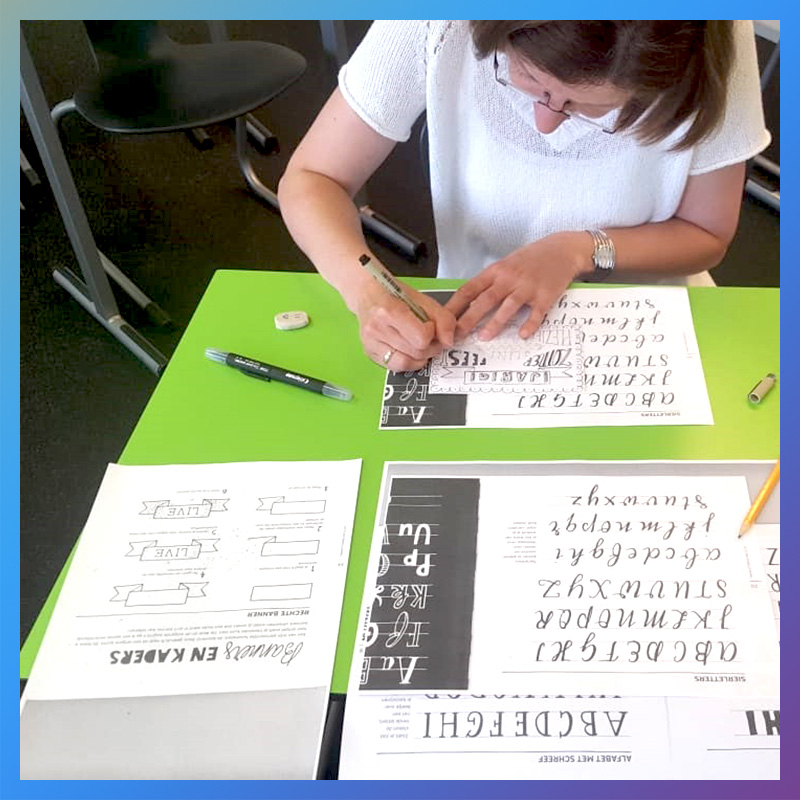 Vrouw oefent verschillende schrijfletters tijdens een workshop handlettering