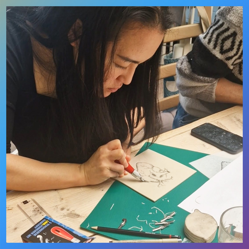 Jongedame gutst een hart uit linorubber bij een linoworkshop van Wauw Workshops in Woerden