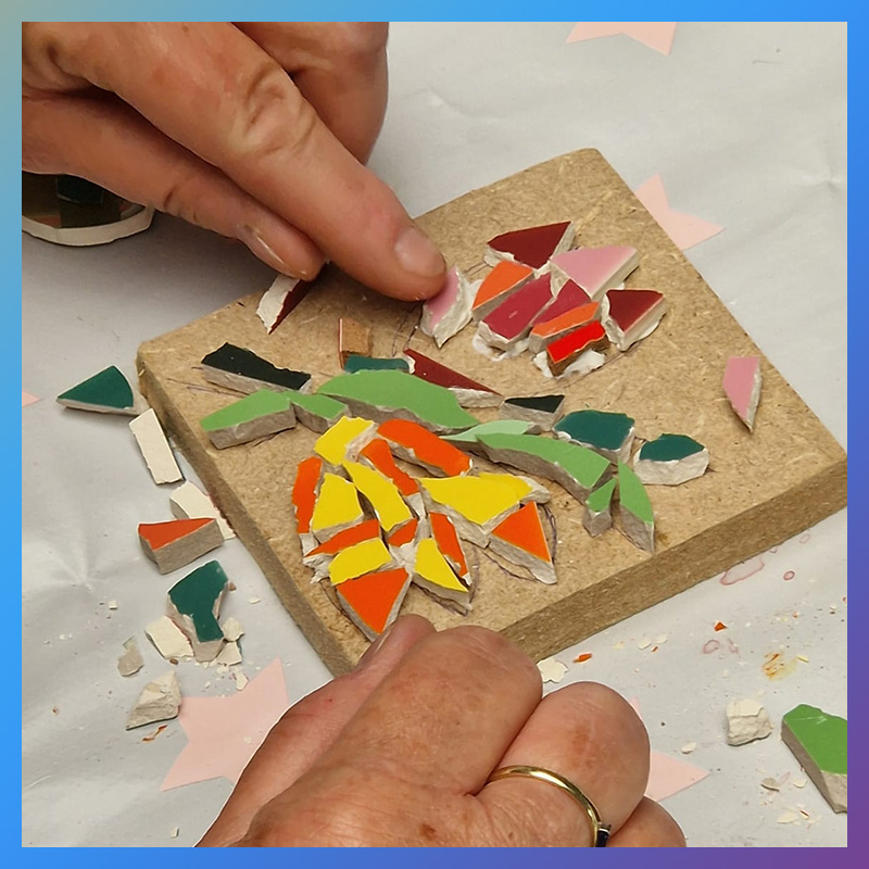 Vrouw maakt een bloem van mozaïeksteentjes bij een workshop van Wauw Workshops in Woerden